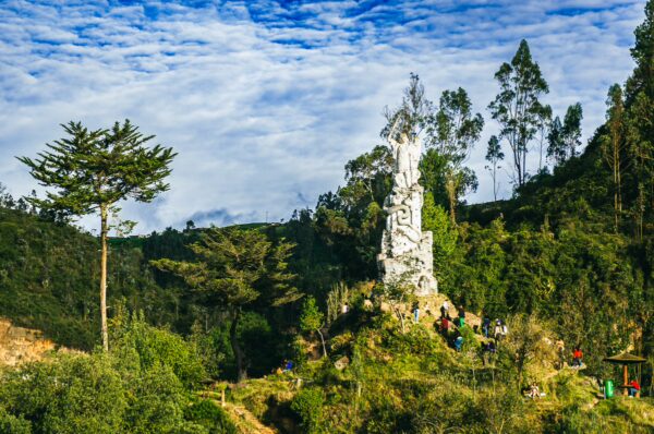 A striking white monument stands amidst lush greenery and a clear blue sky in Las Lajas, Nariño, Colombia.