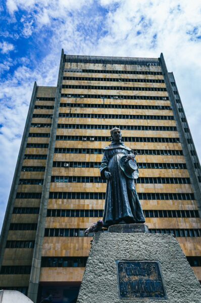 Bronze statue of a historical figure in the Plazoleta de San Francisco, with a tall modern building in the background, Cali, Valle del Cauca.