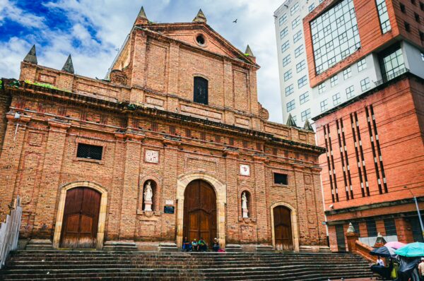 Iglesia de San Francisco features a striking red brick facade surrounded by modern buildings in Cali, Valle del Cauca, Colombia.