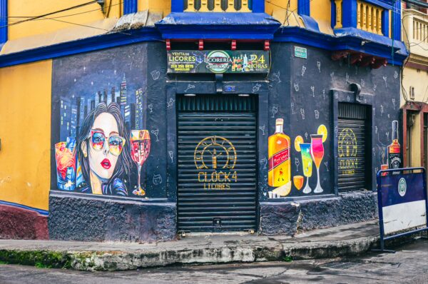Vibrant mural featuring a woman with drinks, adorning a colorful bar facade in Ipiales, Nariño, Colombia.