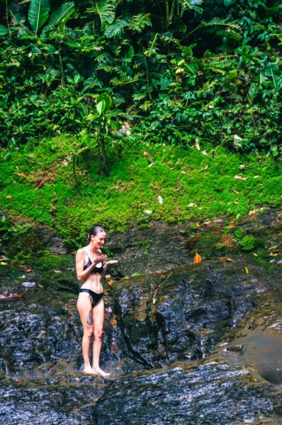 A traveler stands on a rocky creek surrounded by lush greenery in La Siepe, Uramba, Valle del Cauca, Colombia.