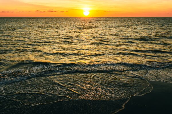 Golden sunset reflecting on the tranquil waves of the ocean at Ladrilleros, Valle del Cauca, Colombia.
