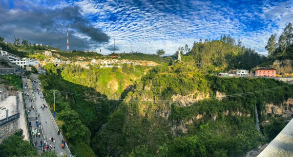 Lush green hills and a deep valley with visitors along the path, showcasing the stunning landscape near Las Lajas, Nariño, Colombia.