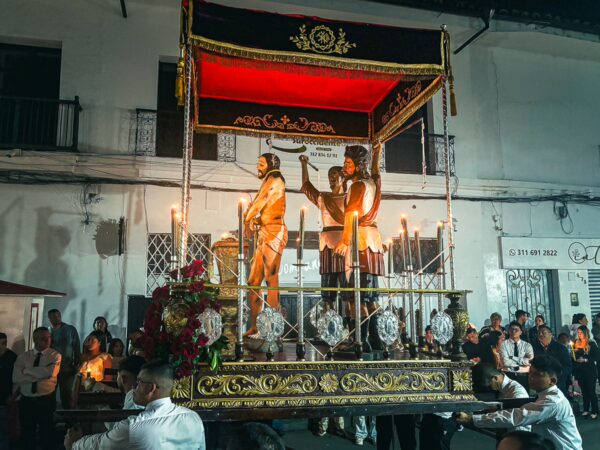 Vibrant procession in Popayán, Colombia, showcasing ornate statues on a decorated float surrounded by an attentive crowd.