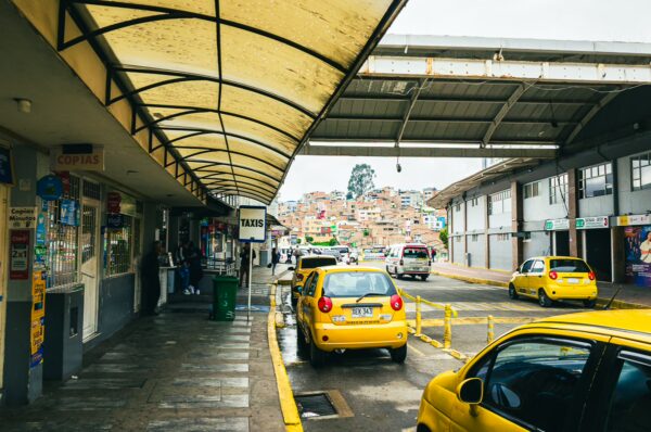 Bright yellow taxis line the bus terminal in Ipiales, Nariño, with a bustling street and colorful buildings in the background.