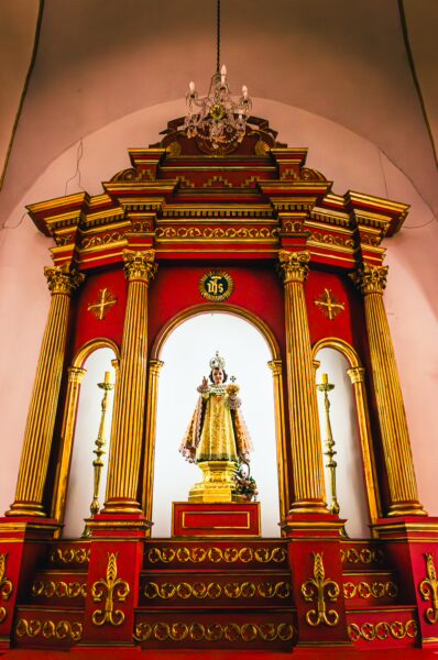 Golden altar featuring a statue of San Pedro, adorned with ornate details in red and gold, inside the Catedral San Pedro, Cali, Colombia.