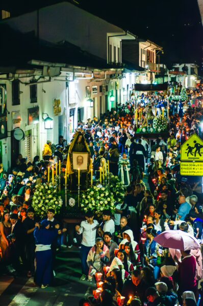 Candlelit procession in Popayán, Colombia, with a large floral display and a vibrant crowd celebrating during the festival.