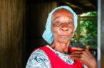 Elderly woman with a blue headscarf and red apron stands near a doorway, showcasing local culture in Uramba Bahía Málaga, Colombia.