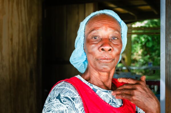 Elderly woman with a blue headscarf and red apron stands near a doorway, showcasing local culture in Uramba Bahía Málaga, Colombia.