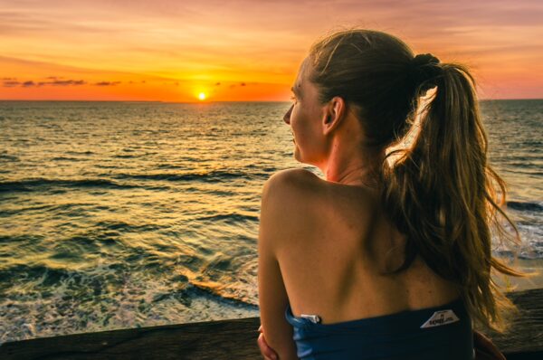 Sunset over the ocean at Ladrilleros, Valle del Cauca, with a woman enjoying the view and warm hues in the sky.