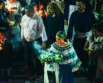 Traditional celebration in Popayán, Cauca, Colombia, featuring a woman in a colorful dress carrying flowers amid a lively crowd.