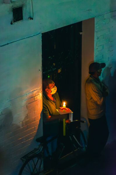 Candle-lit street scene in Popayán, Cauca, Colombia, showcasing figures in warm light against cool-toned walls.