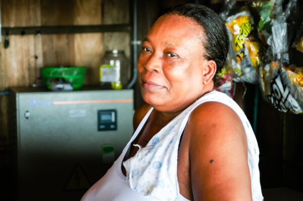 A smiling local woman in a brightly lit wooden stall at Chucheros Beach, showcasing vibrant colors and a welcoming atmosphere in Uramba, Valle del Cauca.