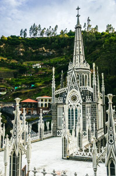 Stunning Las Lajas Sanctuary features intricate gothic architecture, surrounded by lush green hills in Nariño, Colombia.
