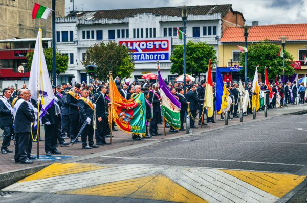 Colorful flags and banners wave amidst a crowd in Parque 20 de Julio, Ipiales, Nariño, Colombia, during a public celebration.