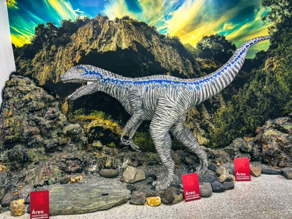 Lifelike dinosaur sculpture with blue stripes, set against a vibrant backdrop, at the Natural History Museum in Popayán, Cauca, Colombia.