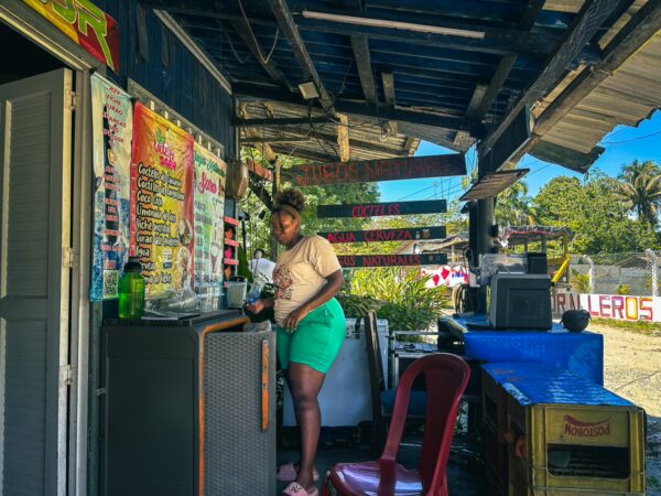 Vibrant scene in Ladrilleros, Valle del Cauca, Colombia, featuring a woman at a colorful beachside kiosk amid lush greenery.