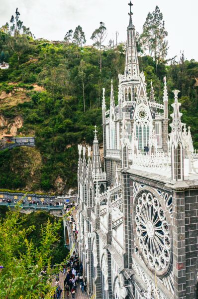 Las Lajas Sanctuary's striking Gothic architecture stands against lush green hills in Nariño, Colombia, attracting visitors year-round.
