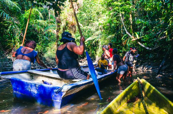 Colorful canoe navigates through lush greenery in Ladrilleros, Valle del Cauca, showcasing local people engaged in fishing activities.