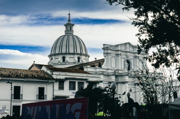 Assumption Cathedral features a prominent dome against a cloudy sky, set within the vibrant architecture of Popayán, Cauca, Colombia.