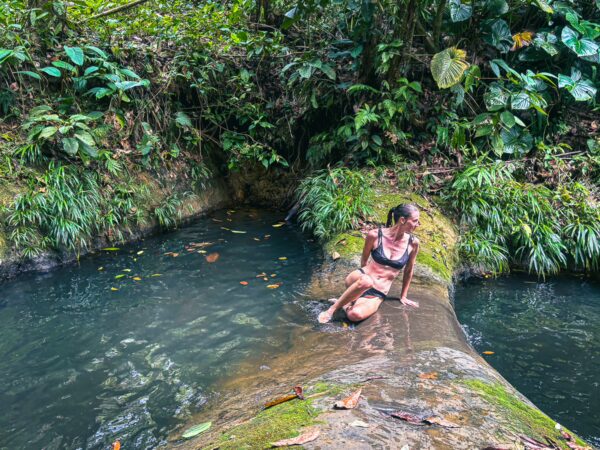 A woman relaxes by the tranquil waters of Tres Marias in Uramba, Bahia Malaga, surrounded by lush greenery in Valle del Cauca, Colombia.