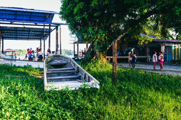 Colorful scenes of local life at Juanchaco, Valle del Cauca, with a boat by lush greenery and people mingling in the background.