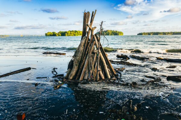 Sticks arranged in a structure on the shoreline, with the tranquil waters of Juanchaco, Valle del Cauca, Colombia, in the background.