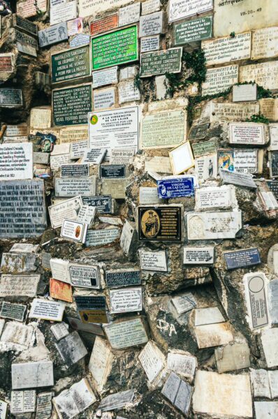 Colorful plaques cover a stone wall at Las Lajas Sanctuary in Nariño, Colombia, creating a mosaic of messages and prayers.