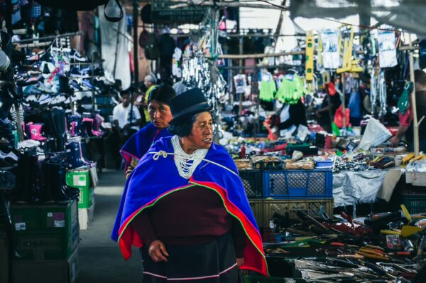 Vibrant market scene in Cauca, Colombia, featuring women in traditional attire among colorful stalls filled with various goods.