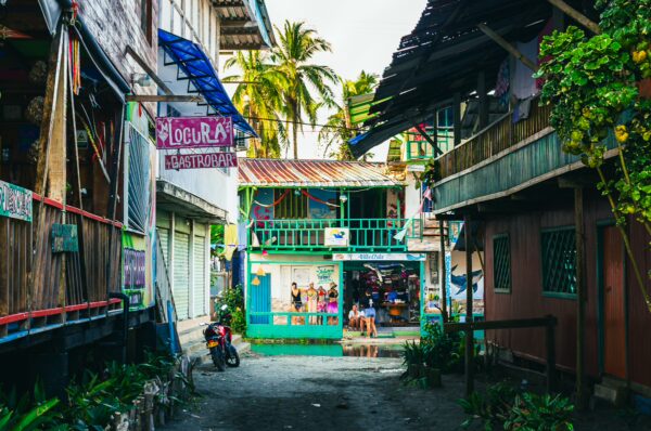 Vibrant street scene in Juanchaco, Valle del Cauca, Colombia, featuring colorful buildings and tropical foliage under a bright sky.