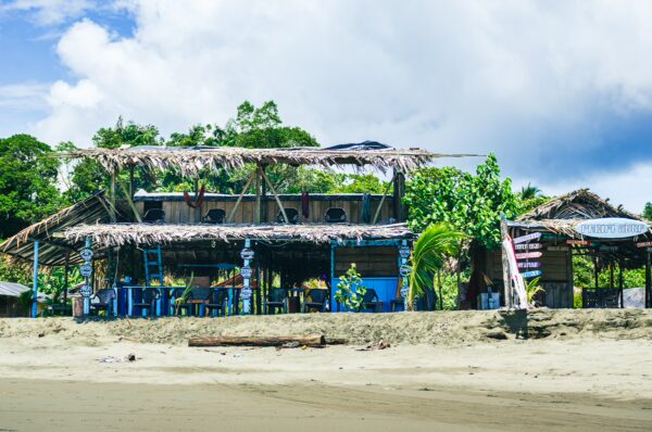 La Barra's vibrant beachside cabana features palm thatching and colorful seating under a cloudy sky in Valle del Cauca, Colombia.