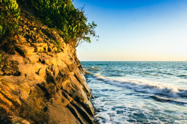 Golden cliffs meet the tranquil waves of the Pacific Ocean at Ladrilleros, Valle del Cauca, Colombia during sunset.