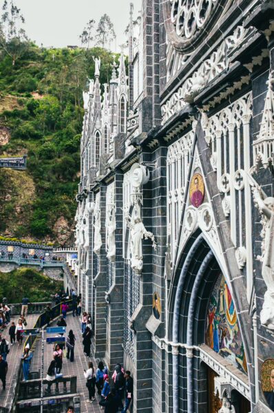 Striking façade of Las Lajas Sanctuary, showcasing intricate architecture, with visitors admiring its beauty in Nariño, Colombia.