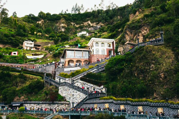 Stunning view of Las Lajas Sanctuary set against lush green hills in Narino, Colombia, with visitors navigating scenic staircases.
