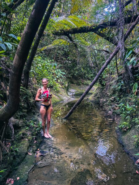 Natural pool surrounded by lush greenery and trees in Ladrilleros, Valle del Cauca, Colombia, with a person enjoying the water.