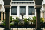 Stone fountain surrounded by lush greenery in a courtyard framed by elegant arches in Popayán, Cauca, Colombia.