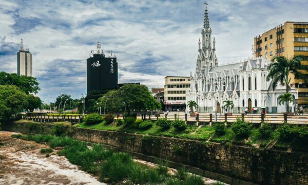 La Ermita stands tall with its striking white façade against a cloudy sky, surrounded by lush greenery in Cali, Valle del Cauca.