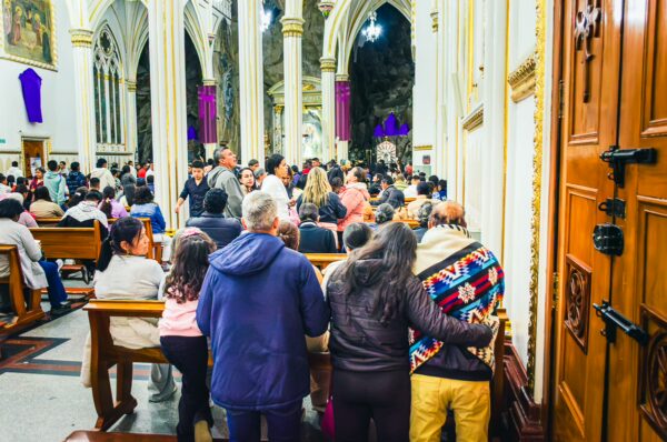 Crowds gather inside Las Lajas Sanctuary in Nariño, Colombia, surrounded by stunning architectural details and vibrant colors.