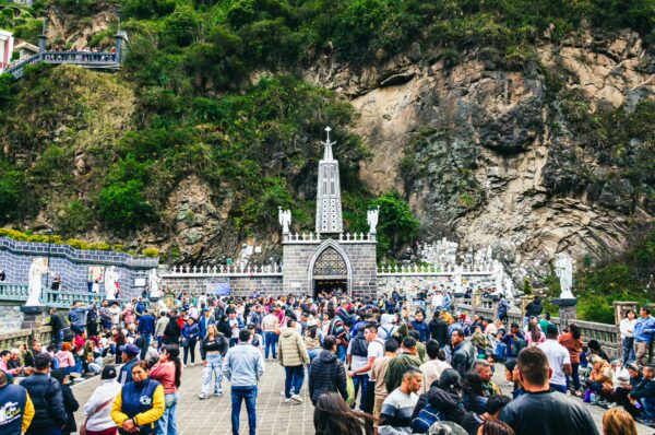Crowds gather near the striking Las Lajas Sanctuary, framed by rugged cliffs and lush greenery in Nariño, Colombia.