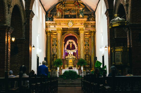 Intricate altar adorned with gold details and purple drapery, set within the historic Claustro de Santo Domingo, Popayán, Cauca, Colombia.