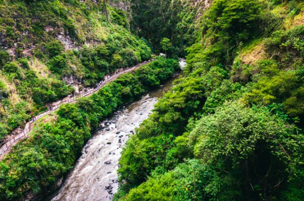 Lush green hills surround a winding river in Las Lajas, Nariño, Colombia, showcasing vibrant foliage and stunning natural beauty.