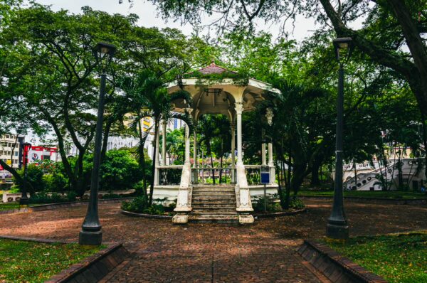 White gazebo surrounded by lush greenery and pathways in Parque La Retreta, Cali, Valle del Cauca, Colombia.