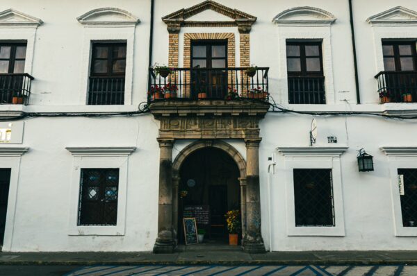 Charming colonial architecture in Popayán, Cauca, Colombia, featuring a stone archway, wooden balconies, and potted plants.