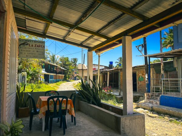 Rustic scene in Ladrilleros, Valle del Cauca, Colombia, featuring a cozy table under a shaded roof and surrounding greenery.