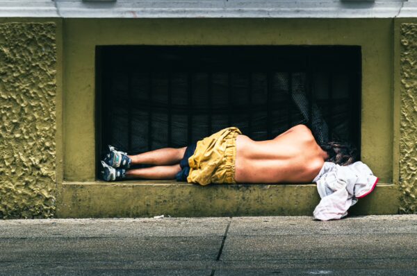A person resting on the sidewalk in Valle del Cauca, Colombia, wearing yellow shorts and surrounded by a minimalist urban setting.