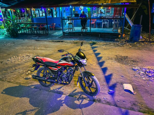 Motorcycle parked on a colorful street in Ladrilleros, with vibrant lights and a relaxed atmosphere in Valle del Cauca, Colombia.