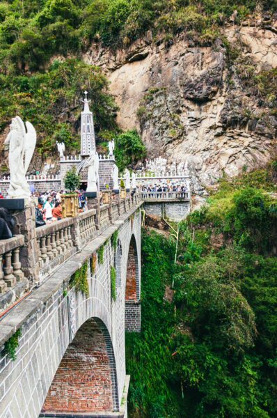 Stunning architecture of Las Lajas Sanctuary bridge, surrounded by lush greenery and rocky cliffs in Narino, Colombia.