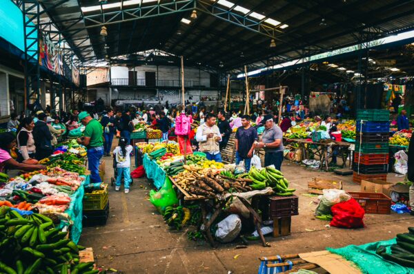 Vibrant market scene in Cauca, Colombia, bustling with people and colorful displays of fresh fruits and vegetables.