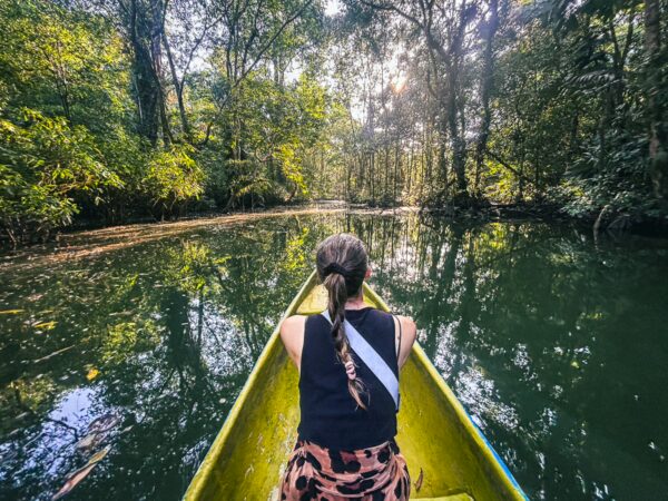 Kayaking through lush greenery at Piscina Natural Pachenda in Ladrilleros, Valle del Cauca, Colombia, reflected in calm waters.