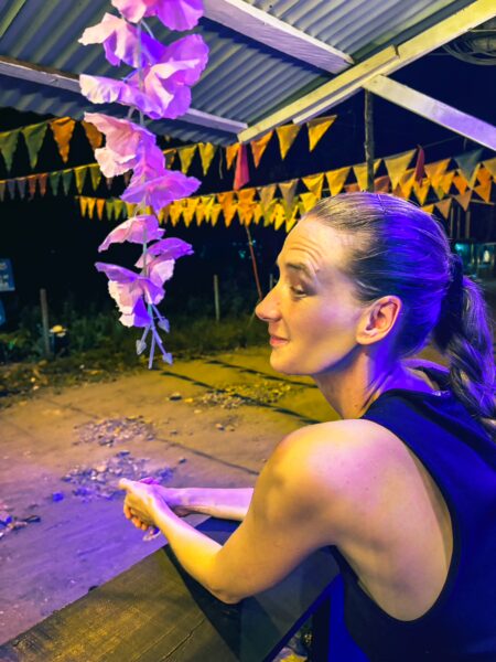 Ladrilleros captures a woman sitting under vibrant papel picado banners, illuminated by soft purple lights at night.